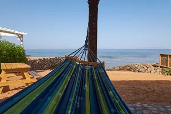 Blick aufs Meer aus der Hängematte am privaten Strand des Twin House Dahab Privater Strand mit Haengematten und Picknicktisch im Twin House Dahab